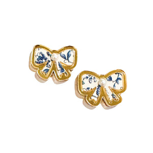 blue and white floral bow shape earring trimmed with gold acrylic. tiny pearl center. 
