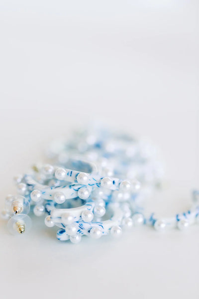 a pile of marbled blue and white acrylic hoops studded with pearls.