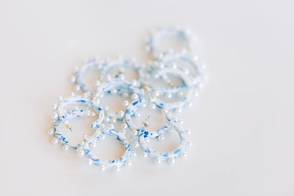 a pile of marbled blue and white acrylic hoops studded with pearls.